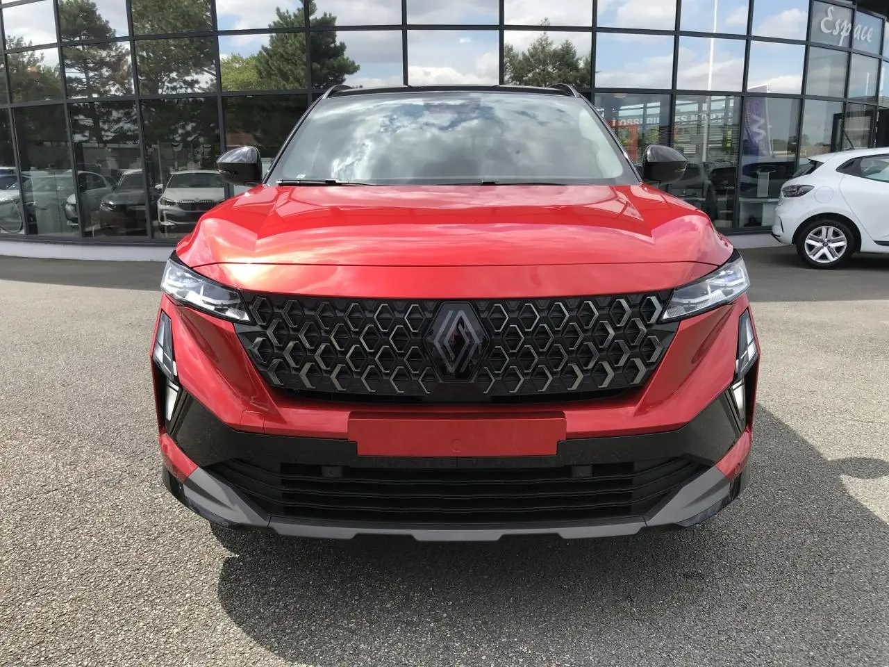 Vue frontale du Renault Austral 2025 bi-ton rouge et noir, mettant en valeur sa calandre hexagonale distinctive.