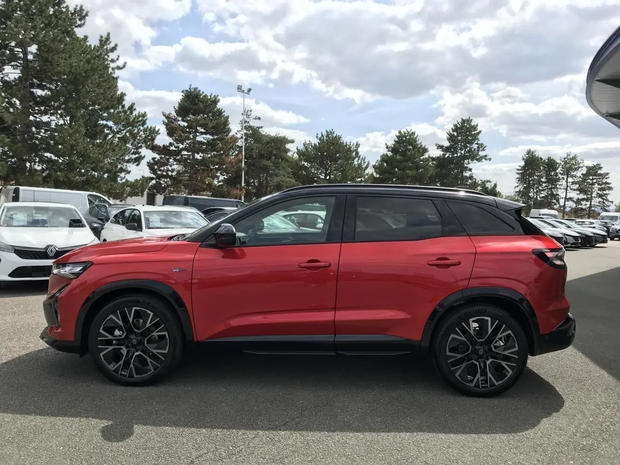 Profil droit du Renault Austral 2025 bi-ton rouge et noir avec jantes alliage noires et toit noir.