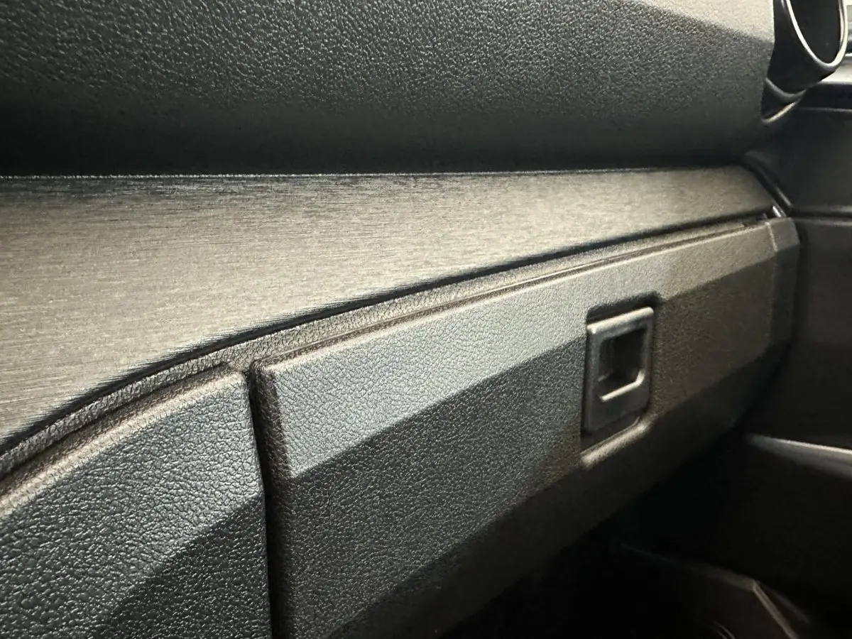 Détail de la boîte à gants noire côté passager de l'AIXAM Ambition E City Pack 2026, intérieur sobre et texturé.