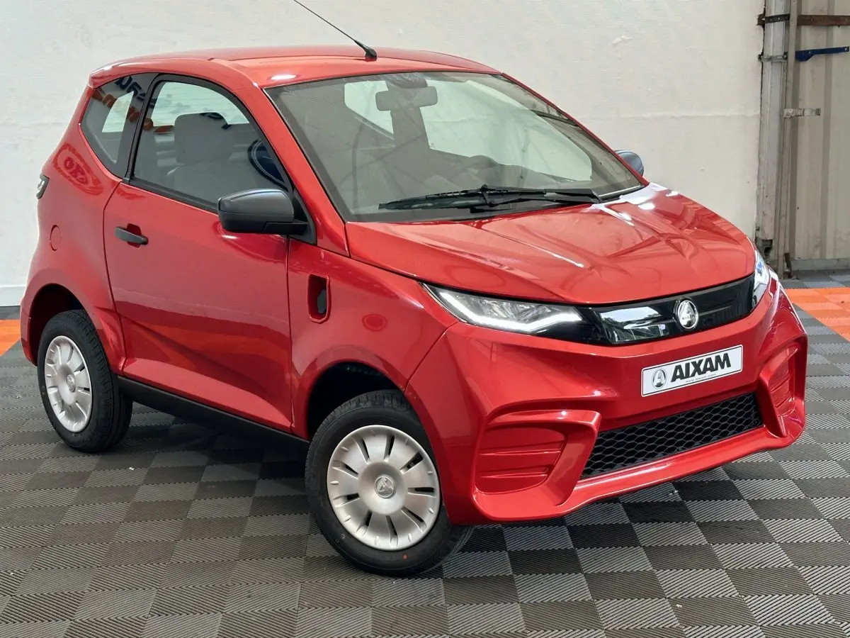 Vue 3/4 avant droite de l'AIXAM AMBITION E CITY PACK rouge 2026 avec rétroviseur caméra côté conducteur.