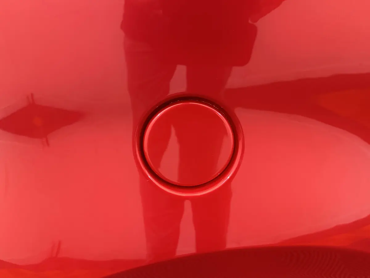 Gros plan sur la trappe de recharge rouge de l'AIXAM AMBITION E CITY PACK 2026, vue de côté conducteur.