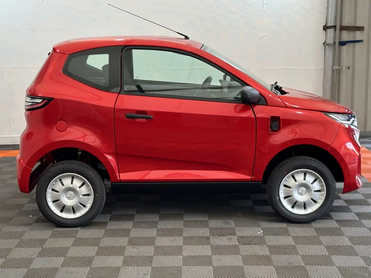 Vue de profil côté gauche d'une Aixam Ambition E City Pack rouge électrique avec rétroviseur caméra conducteur.