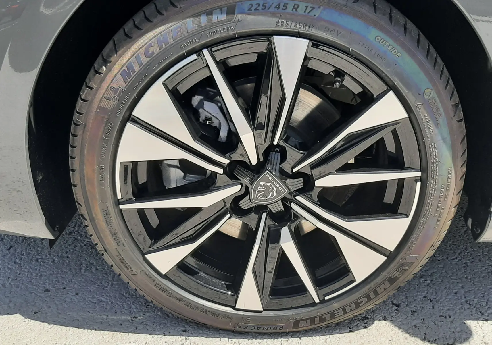 Gros plan sur la jante noire et argentée avec logo Peugeot d'une 308 gris selenium, pneu Michelin visible.