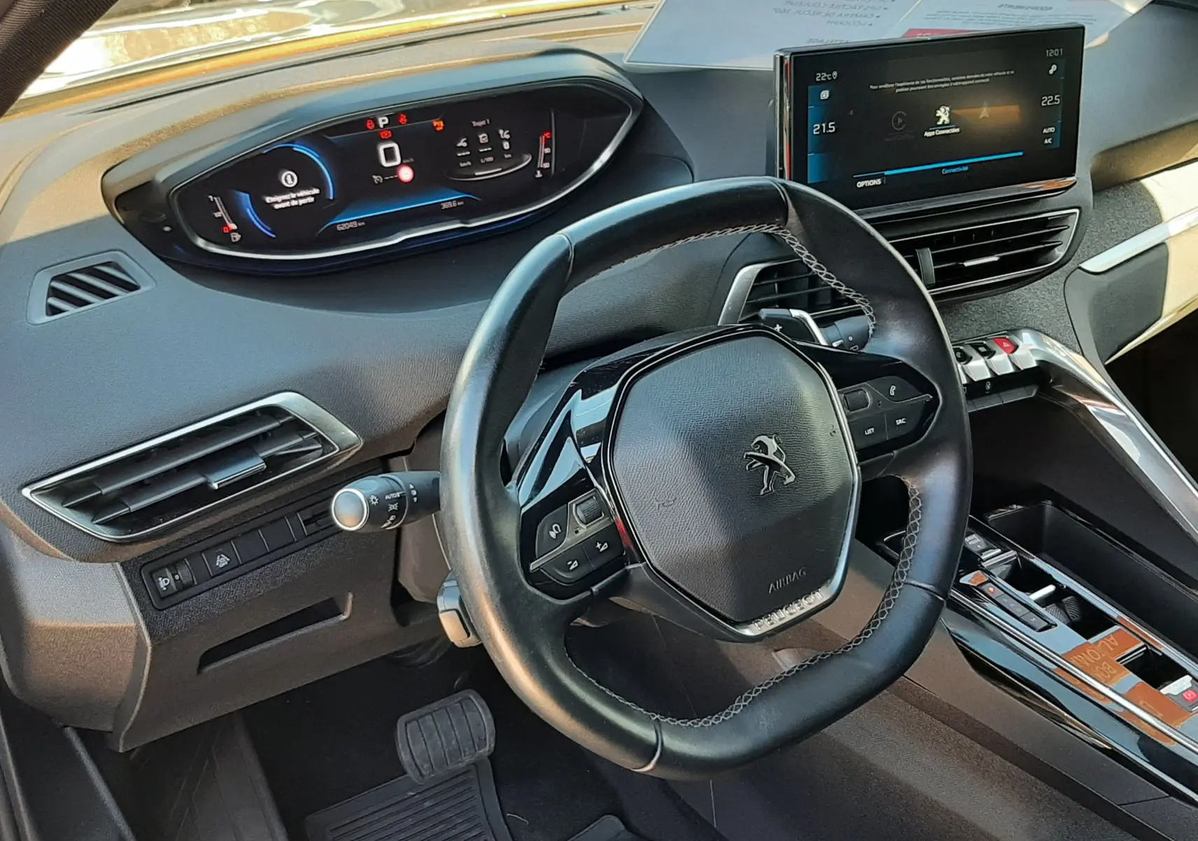 Vue intérieure du poste de conduite du Peugeot 3008 gris platinium, avec volant compact et tableau de bord numérique lumineux.