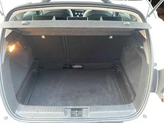 Coffre ouvert vu de l'arrière d'un Renault Captur blanc nacré avec intérieur noir, montrant un espace de chargement vide.