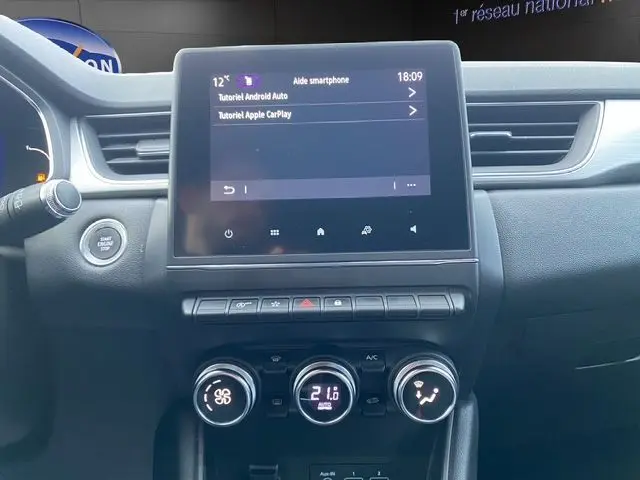 Vue intérieure du tableau de bord du Renault Captur 2021, écran tactile central avec commandes climatisation et bouton start/stop.