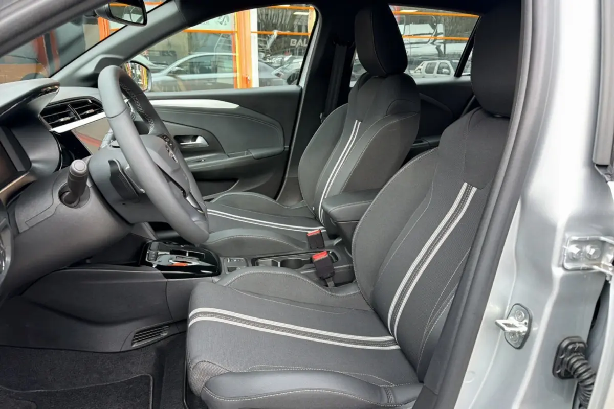 Vue intérieure côté conducteur de l’Opel Corsa gris kristall, sièges tissu avec bandes blanches et volant multifonctions.