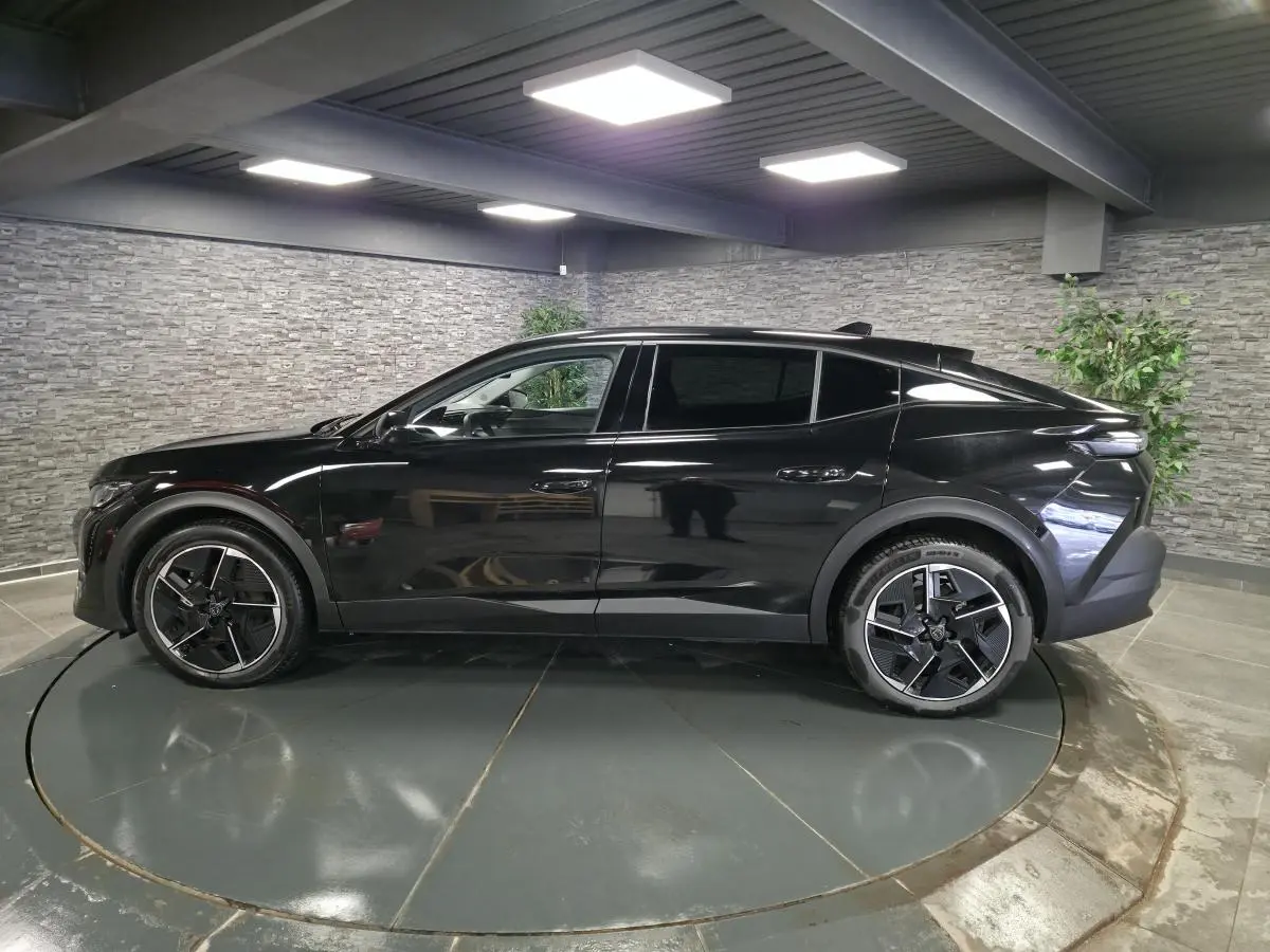 Profil côté gauche d'une Peugeot 408 électrique 2024 noire Perla Nera avec jantes alliage 19 pouces diamantées.