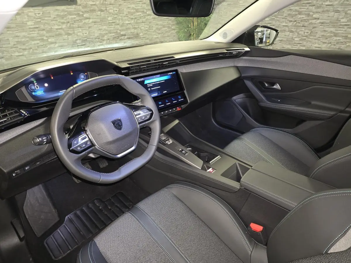 Intérieur avant droit du Peugeot 408 électrique 2024, volant compact, écran tactile 10 pouces et sellerie tri-matières noire.