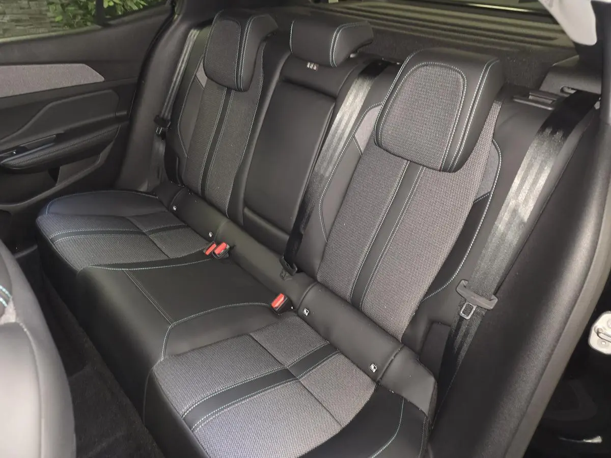 Vue intérieure sur la banquette arrière du Peugeot 408 2024, sellerie tri-matières noire avec surpiqûres bleues.
