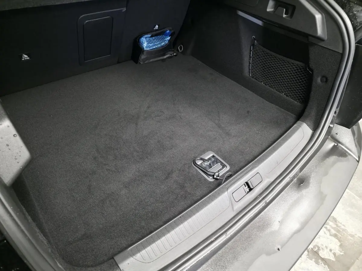 Coffre ouvert du Peugeot 408 noir Perla Nera, vue plongeante montrant un espace de chargement propre avec filet latéral.