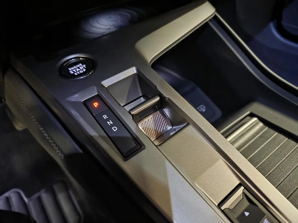 Gros plan sur la console centrale de la Peugeot 408 électrique 2024, montrant la commande de boîte auto et le bouton start/stop.