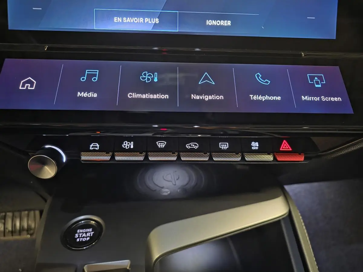 Vue rapprochée de la console centrale tactile et des commandes du Peugeot 408 électrique noir, avec recharge sans fil visible.