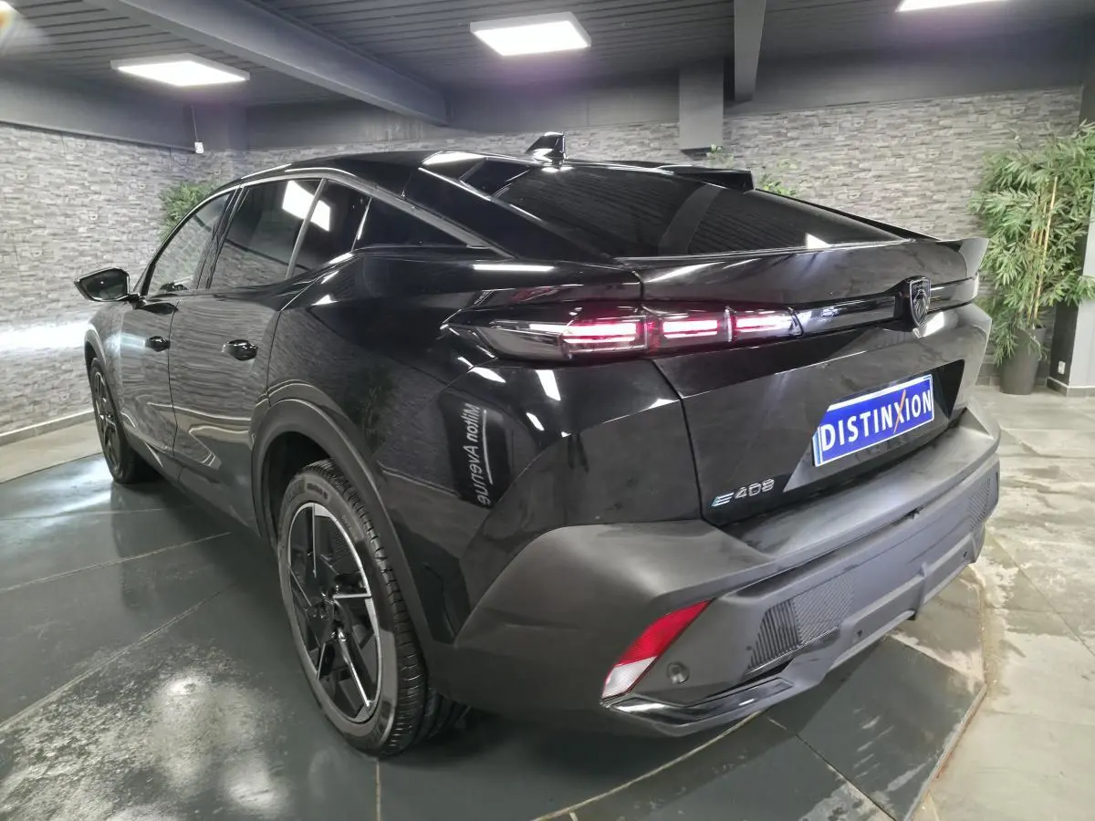 Vue 3/4 arrière droite d’une Peugeot 408 électrique noire Perla Nera avec feux arrière LED et jantes alliage 19 pouces.