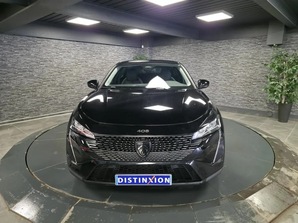 Vue avant d'une Peugeot 408 électrique noire Perla Nera, avec calandre distinctive et phares LED dans un showroom.