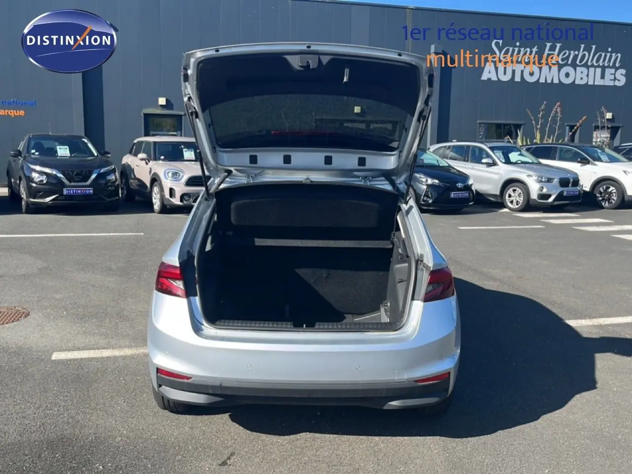 Vue arrière d'une Skoda Fabia Reflex Silver avec coffre ouvert sur un parking extérieur ensoleillé.