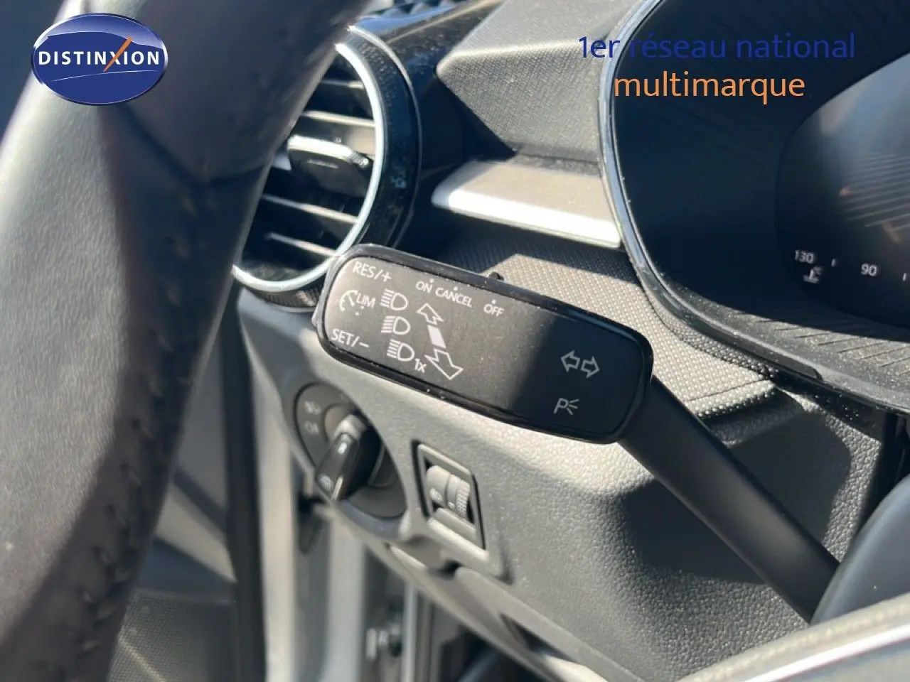 Gros plan sur la commande de régulateur de vitesse à gauche du volant dans l’habitacle gris noir d’une Skoda Fabia Reflex Silver.