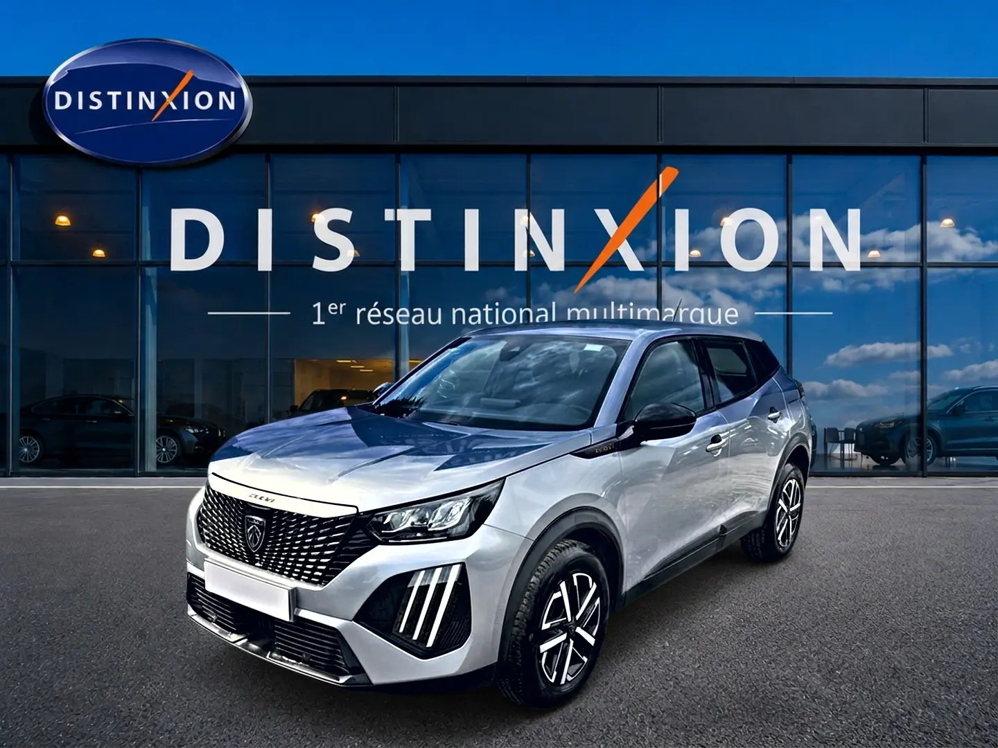 Peugeot 2008 gris en 3/4 avant droit, avec calandre noire et feux LED distinctifs, devant showroom Distinxion.
