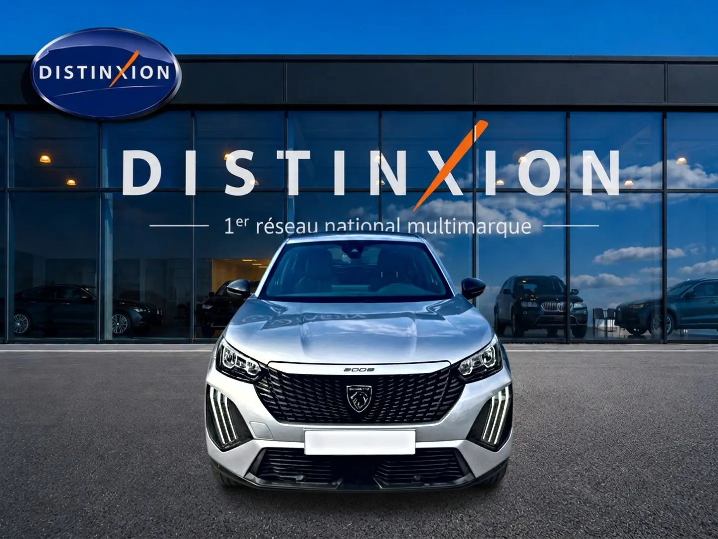 Vue avant d'un Peugeot 2008 gris 2025 avec calandre noire et feux LED verticaux, devant une vitrine Distinxion.
