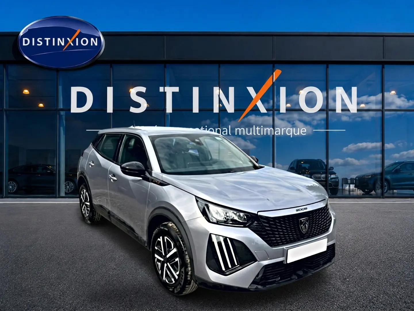 Peugeot 2008 gris en 3/4 avant droit, avec calandre noire et feux LED distinctifs, devant vitrine Distinxion.