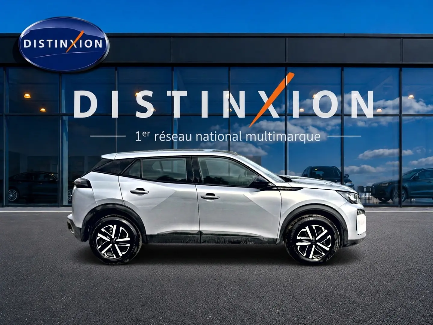 Peugeot 2008 gris en profil droit, soulignant ses jantes noires et détails noirs contrastants, devant une vitrine Distinxion.