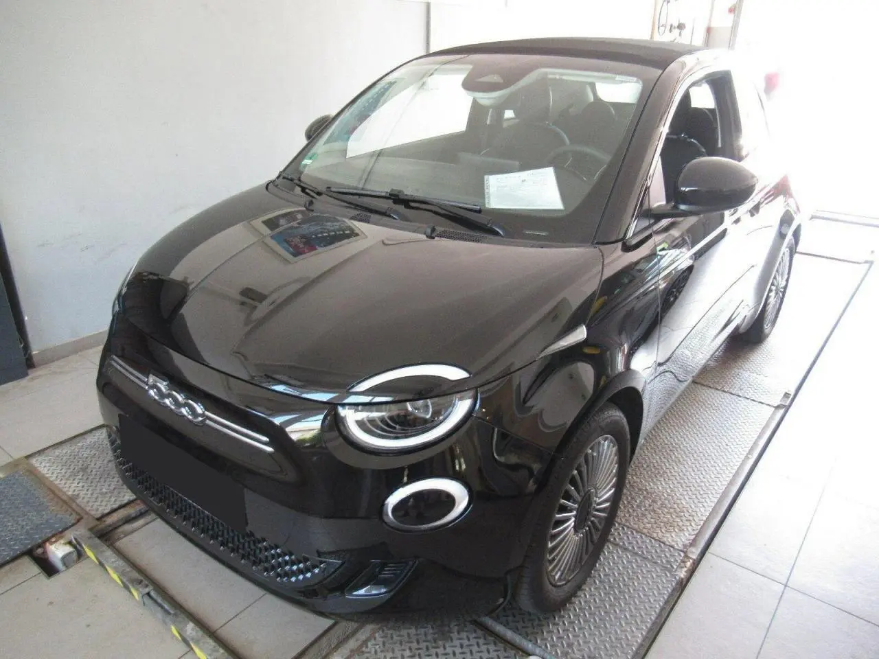 Vue 3/4 avant droite d'une Fiat 500 Cabriolet électrique noire avec jantes alliage 16'' et capote fermée.