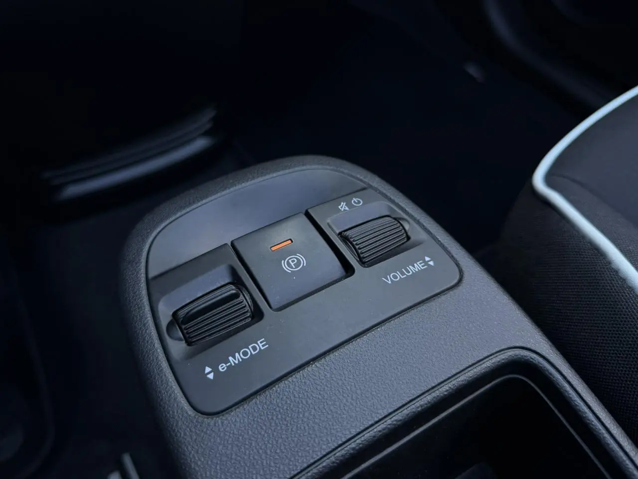 Gros plan sur la console centrale noire de la Fiat 500 Cabriolet électrique, avec commandes e-Mode et volume.