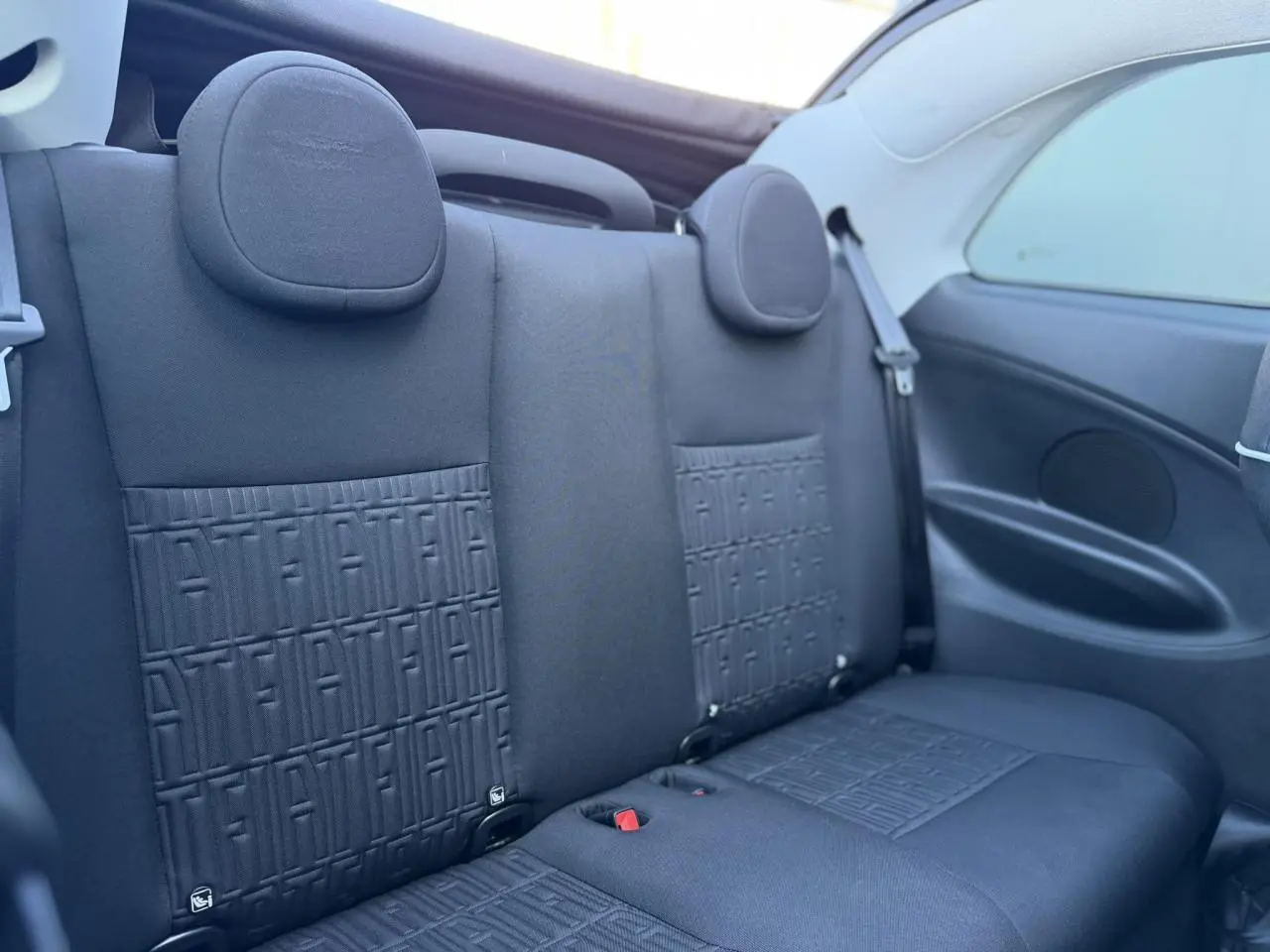 Vue rapprochée de la banquette arrière noire avec motifs FIAT embossés du cabriolet électrique FIAT 500 Icone 2024.