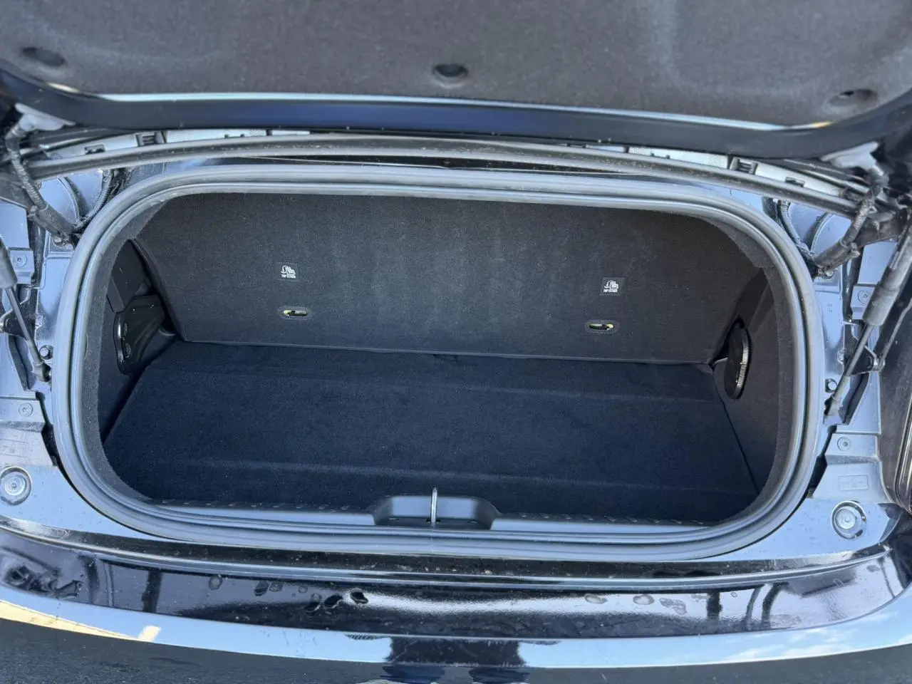 Coffre ouvert vu de dessus de la Fiat 500 Cabriolet électrique noire, montrant un espace de rangement vide et propre.