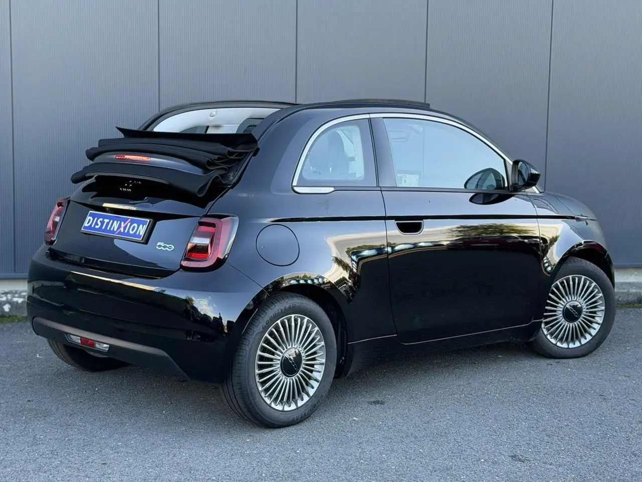 Vue 3/4 arrière droite d'une Fiat 500 Cabriolet électrique noire avec capote repliée et jantes alliage 16 pouces.