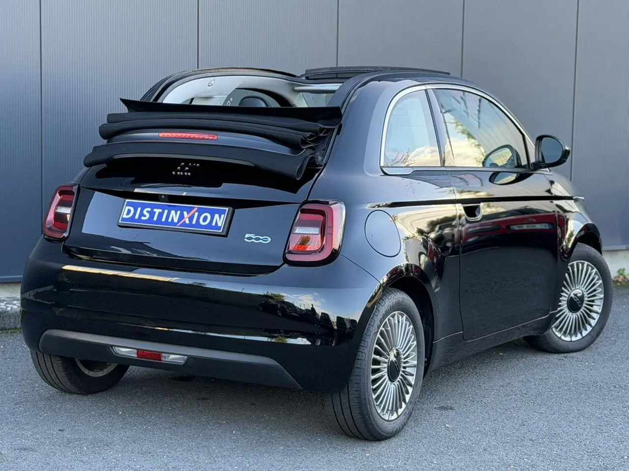 Vue 3/4 arrière droite d'une FIAT 500 cabriolet électrique noire avec capote repliée et jantes alliage 16 pouces.