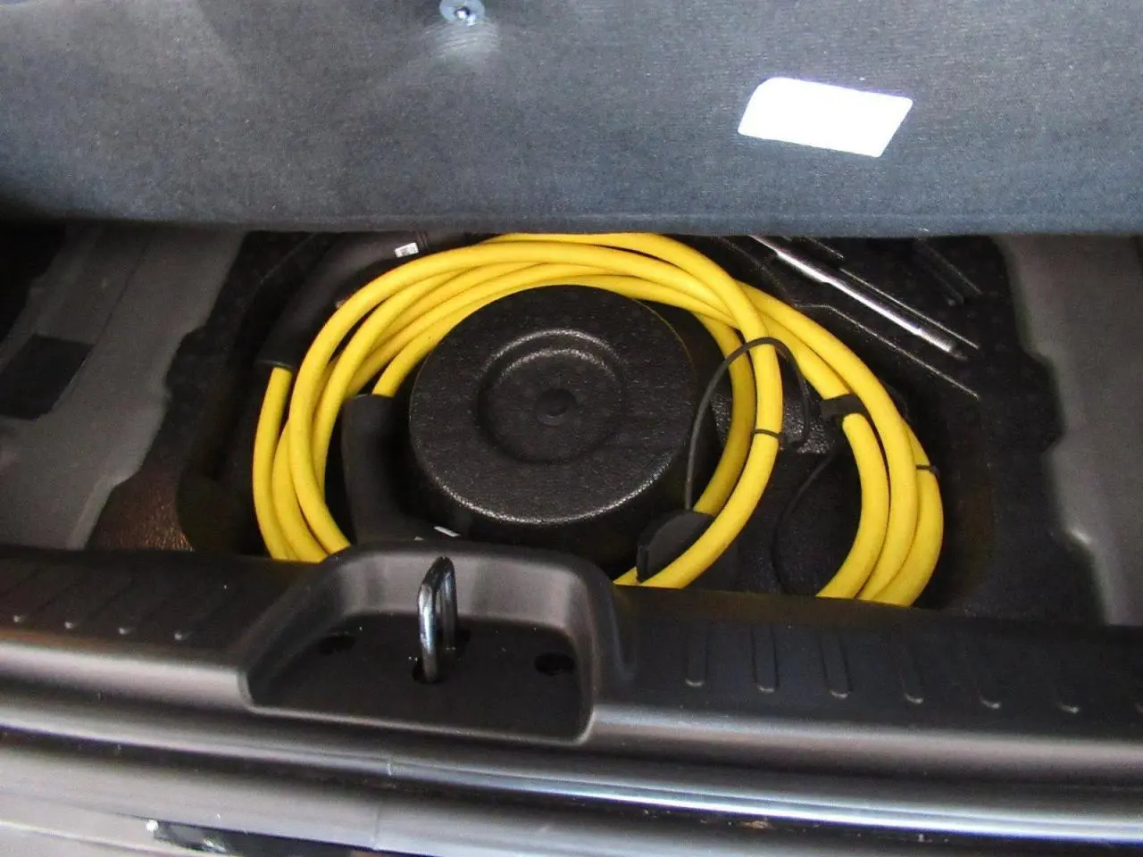 Coffre ouvert du Fiat 500 Cabriolet électrique noir 2024, montrant le câble de recharge jaune enroulé.