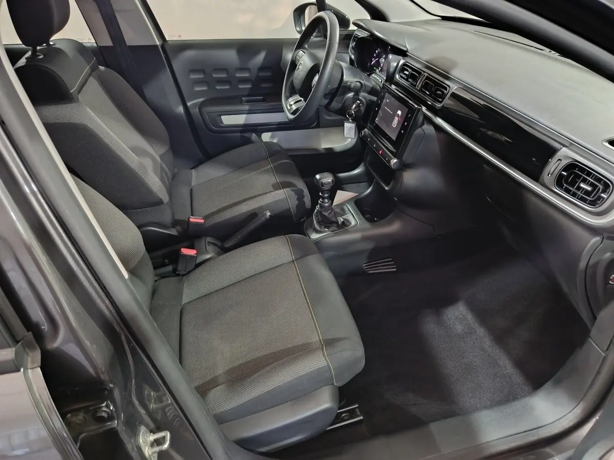 Vue intérieure côté conducteur de la Citroën C3 gris foncé 2024, avec tableau de bord moderne et boîte manuelle.
