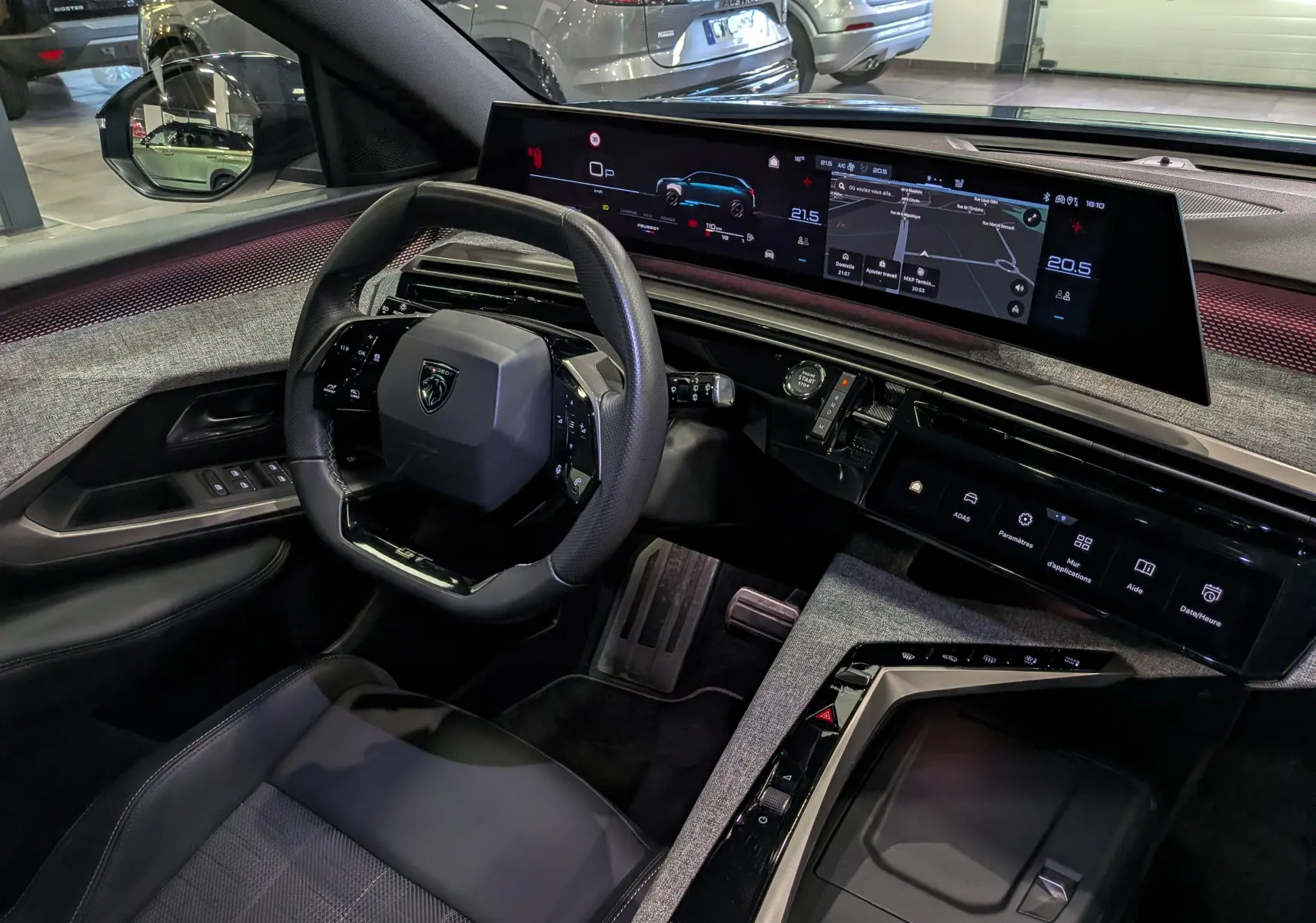Vue intérieure côté conducteur du Peugeot 5008 Hybrid 2025, tableau de bord numérique et volant compact noir.