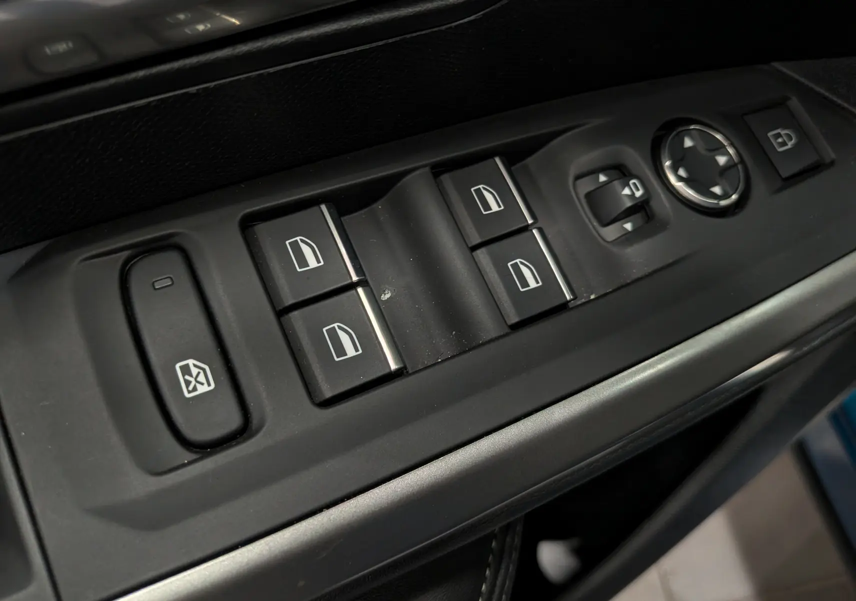 Gros plan sur les commandes des vitres et rétroviseurs côté gauche de la Peugeot 5008 Hybrid 2025, intérieur noir.