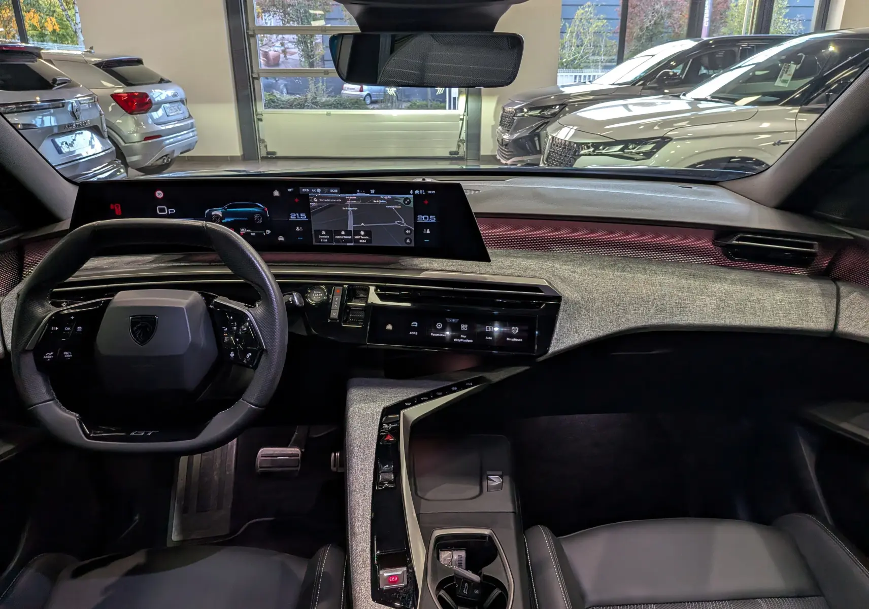 Vue intérieure avant du Peugeot 5008 Hybrid 145 GT 2025, tableau de bord moderne avec écran large et volant compact noir.