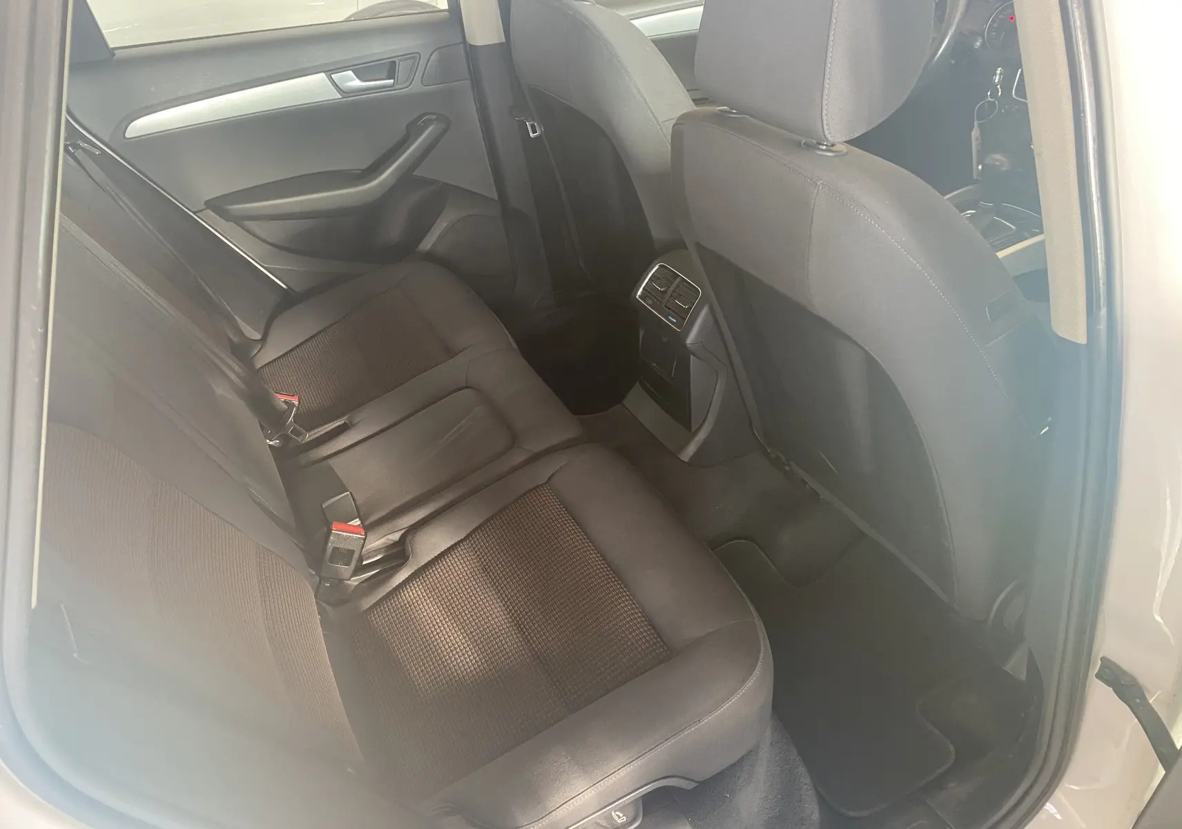 Vue intérieure côté arrière droit de l'Audi Q5 blanc 2012 montrant les sièges arrière en tissu noir et les aérateurs centraux.