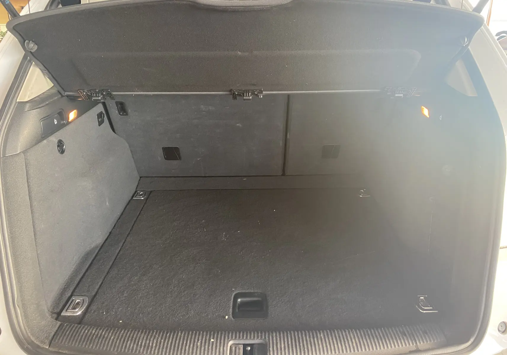 Coffre ouvert d'un Audi Q5 blanc de 2012, montrant un espace de chargement propre et bien éclairé.