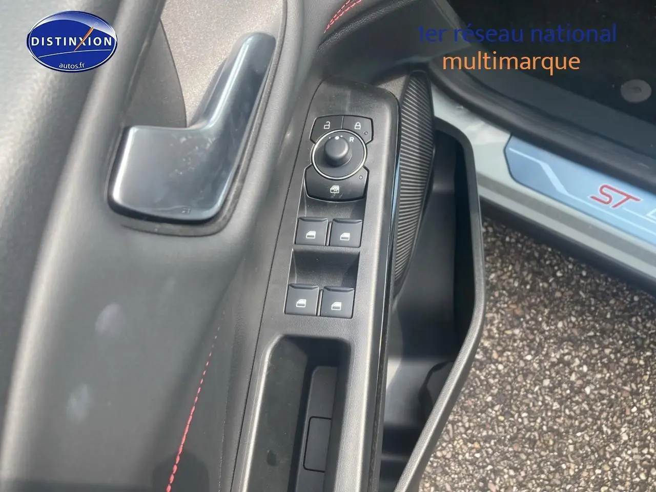 Gros plan sur la commande des vitres côté conducteur du Ford Puma gris cactus avec surpiqûres rouges ST visible sur le seuil de porte.