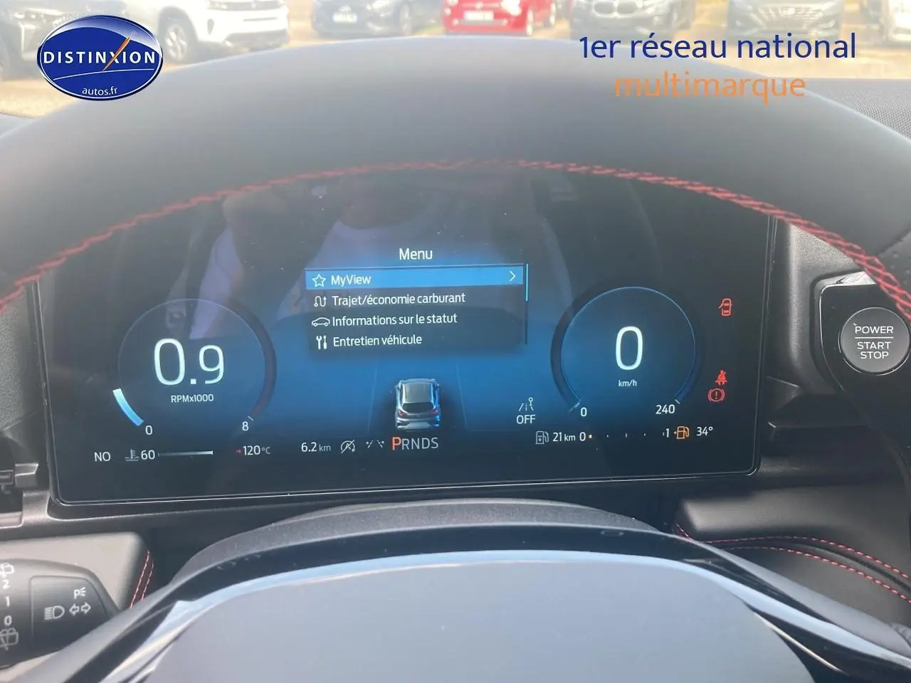 Tableau de bord numérique du Ford Puma 2025 avec affichage du menu et volant avec surpiqûres rouges visibles.