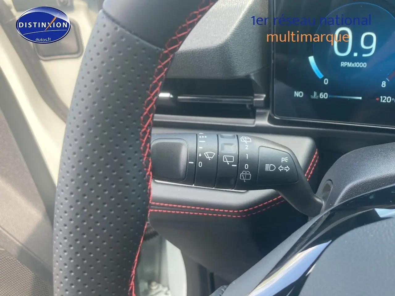 Gros plan sur la commande d’essuie-glace et volant perforé avec surpiqûres rouges du Ford Puma gris cactus 2025.