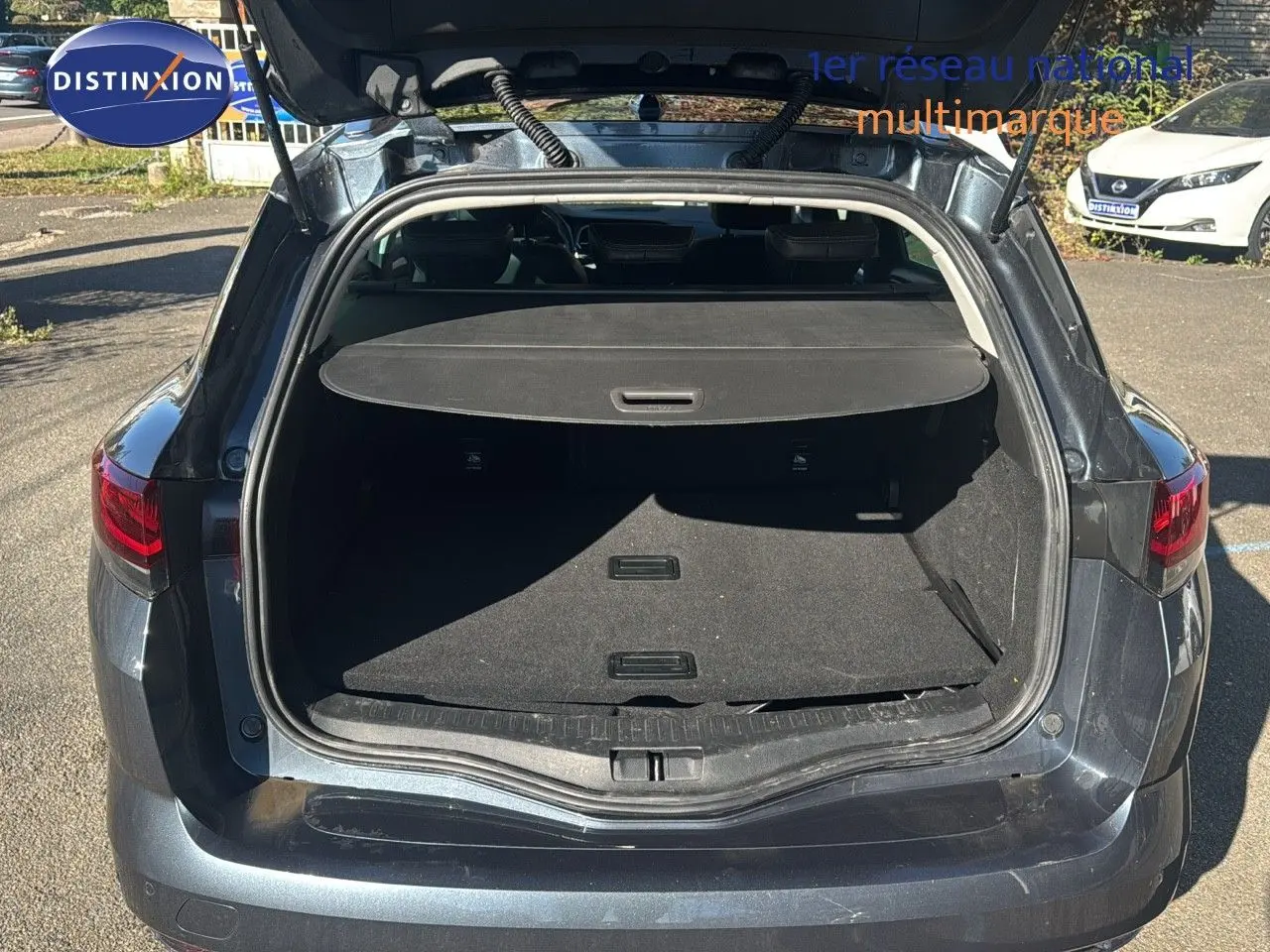 Vue arrière ouverte sur le coffre d'une Renault Mégane Break 2024 gris titanium métal, soulignant l'espace de chargement.