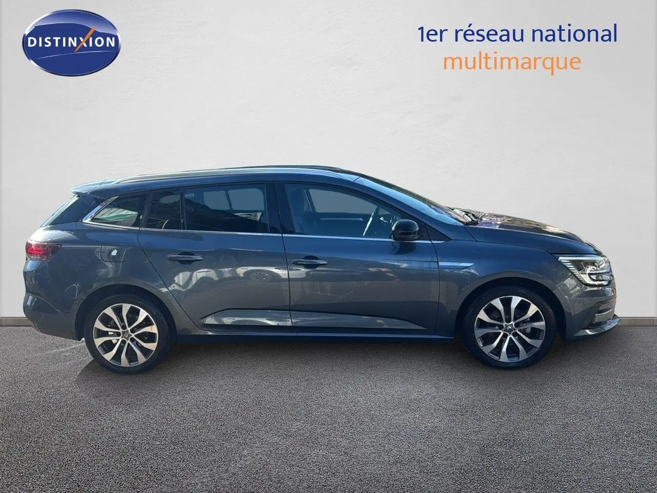 Profil droit de la Renault Mégane Break 1.5 BlueDCI 115ch gris titanium métal avec jantes bi-ton et feux LED allumés.