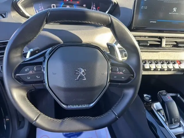Vue rapprochée du volant cuir noir du Peugeot 3008 2023 avec commandes intégrées et tableau de bord digital.