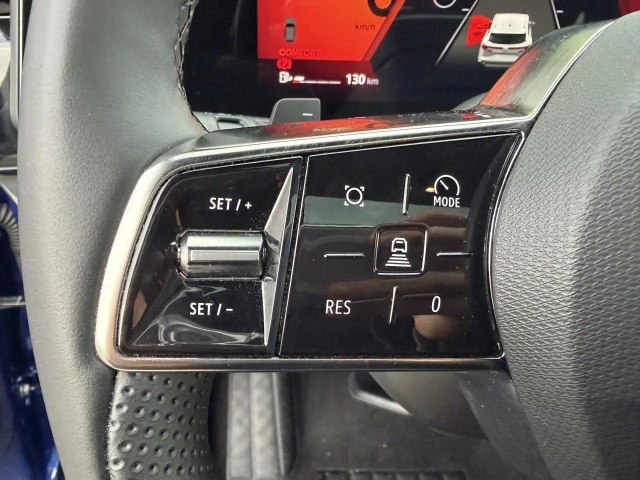 Gros plan sur les commandes de régulateur de vitesse au volant du Renault Austral bleu Iron, intérieur noir.