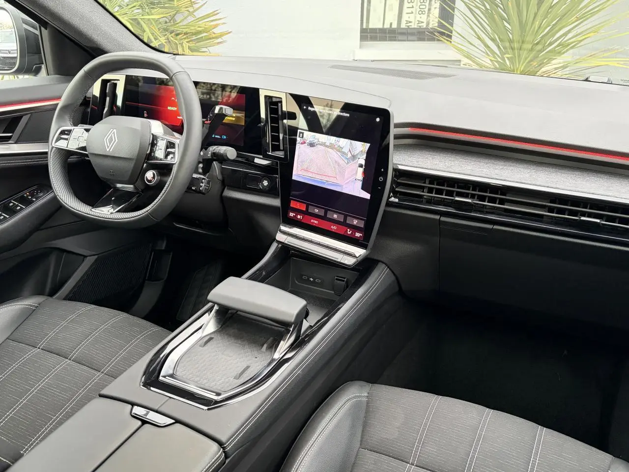 Vue intérieure côté conducteur du Renault Austral E-Tech 2025, tableau de bord noir avec écran tactile central vertical et volant compact.