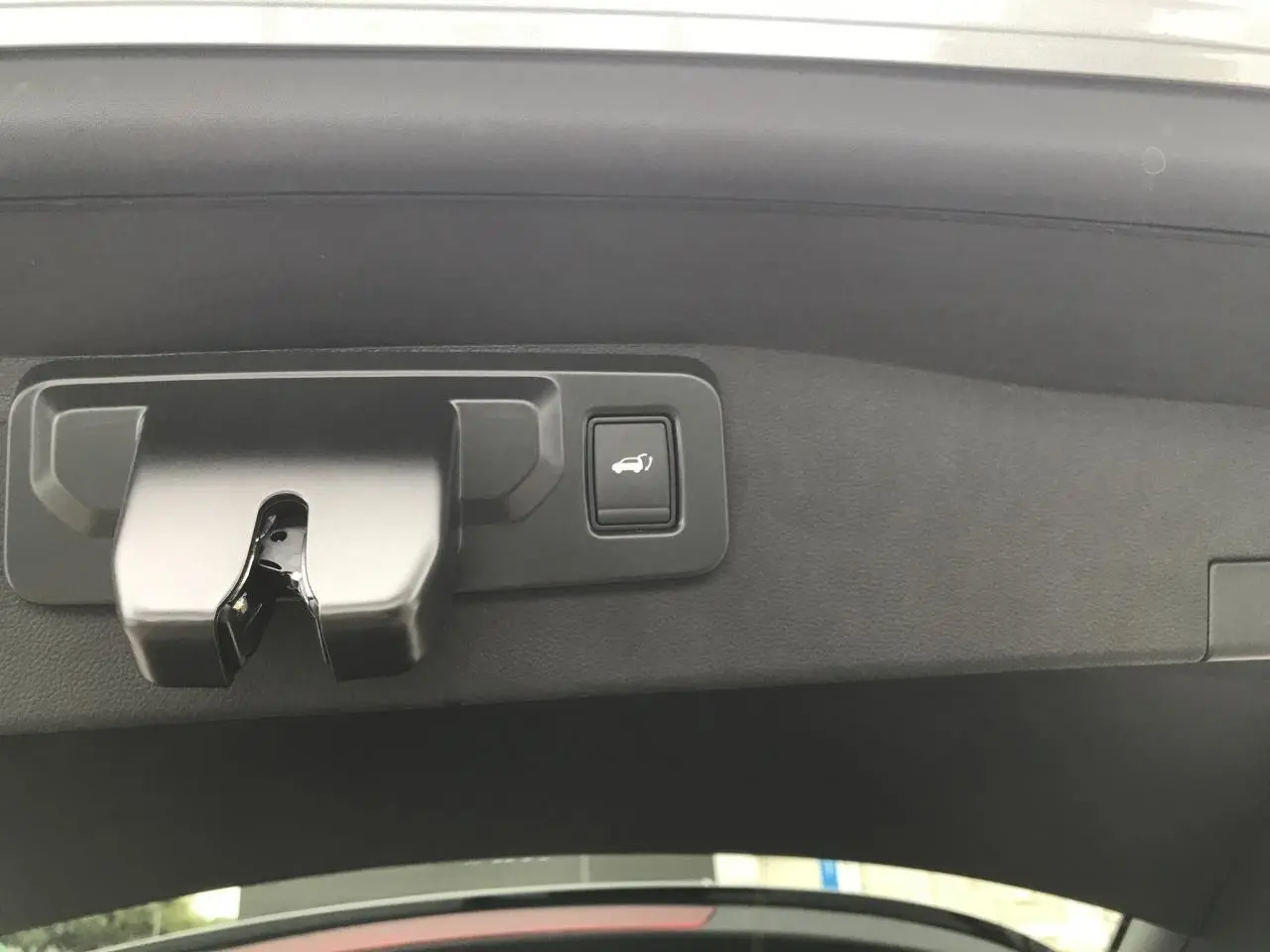 Gros plan sur la serrure et le bouton d'ouverture du hayon motorisé du coffre du Renault Austral gris bi-ton.