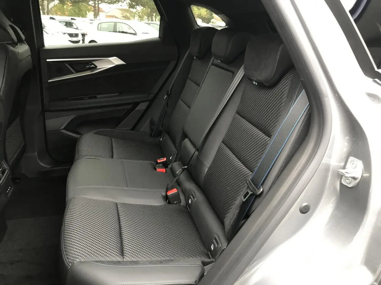 Vue intérieure côté droit sur la banquette arrière gris foncé avec surpiqûres bleues du Renault Austral 2025 bi-ton.