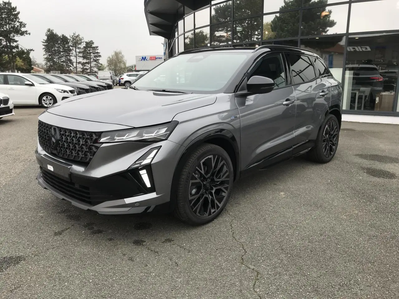 Renault Austral full hybrid gris métallisé et noir, vue 3/4 avant avec jantes noires et calandre distinctive.