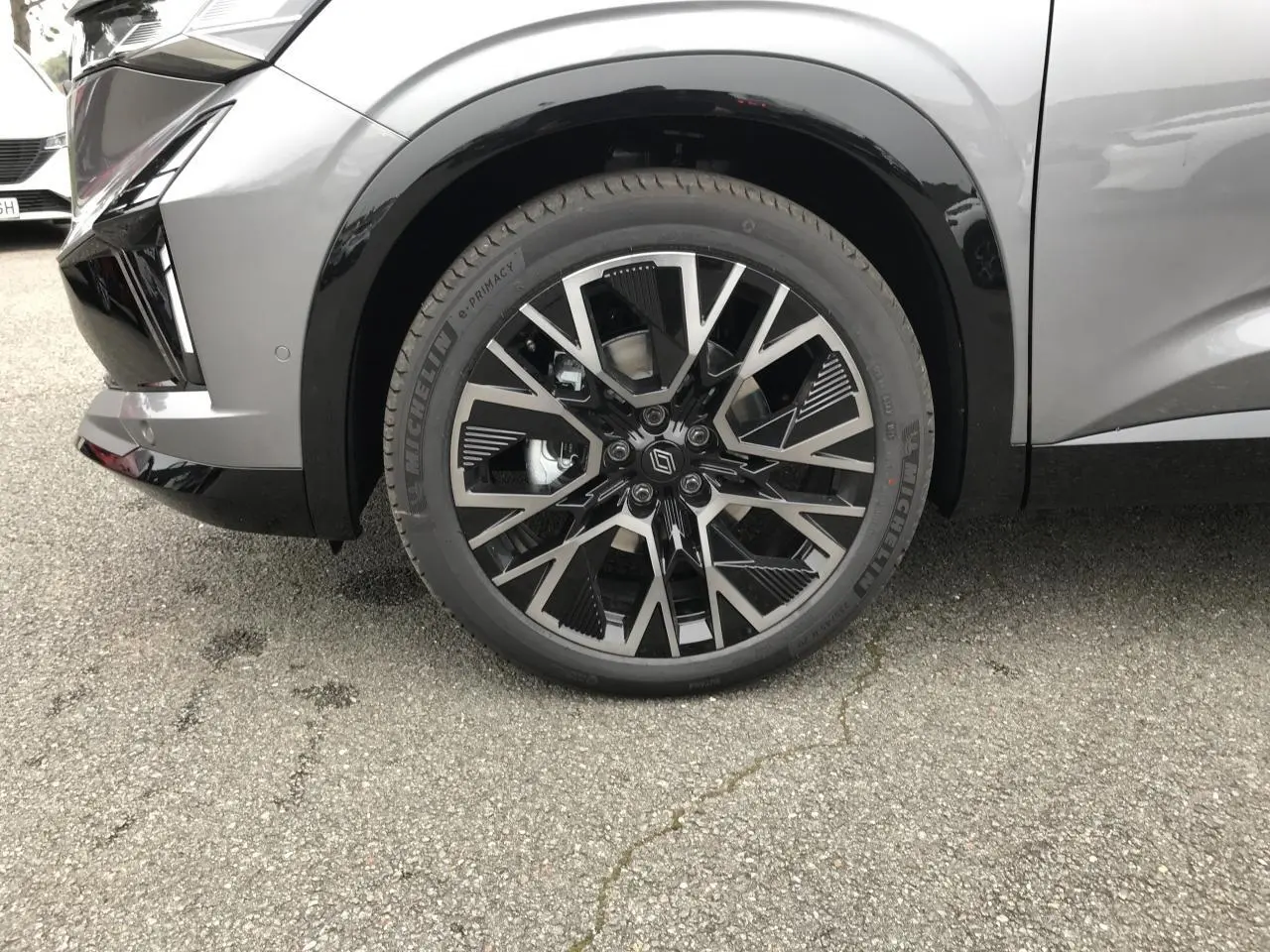 Gros plan sur la roue avant droite du Renault Austral gris bi-ton avec jante alliage 20 pouces noire et grise.